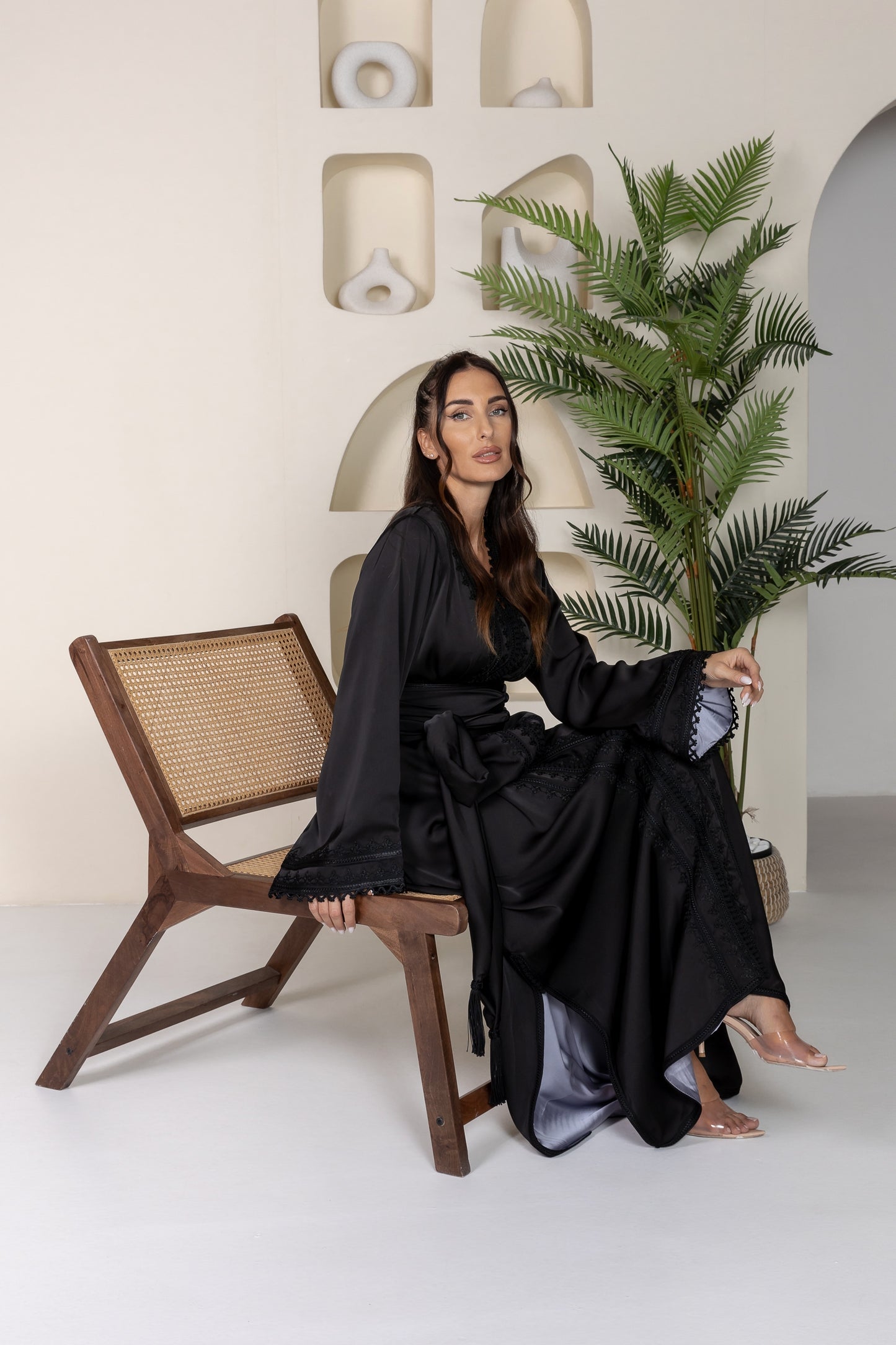 Woman seated in black Moroccan kaftan with embroidered details