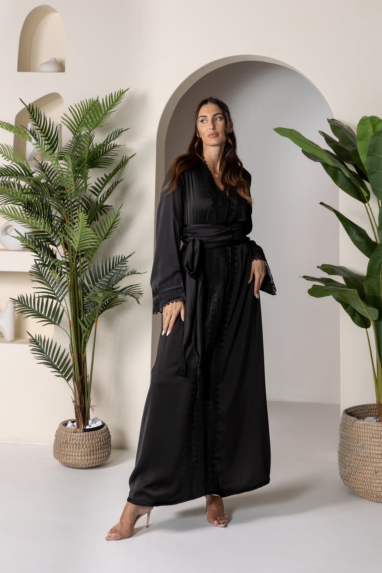 Woman in black Moroccan kaftan with wide sleeves and a matching belt