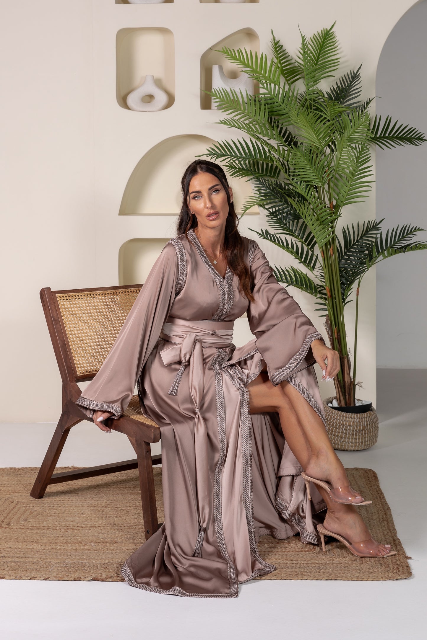 Woman seated in bronze Moroccan kaftan with embroidered details