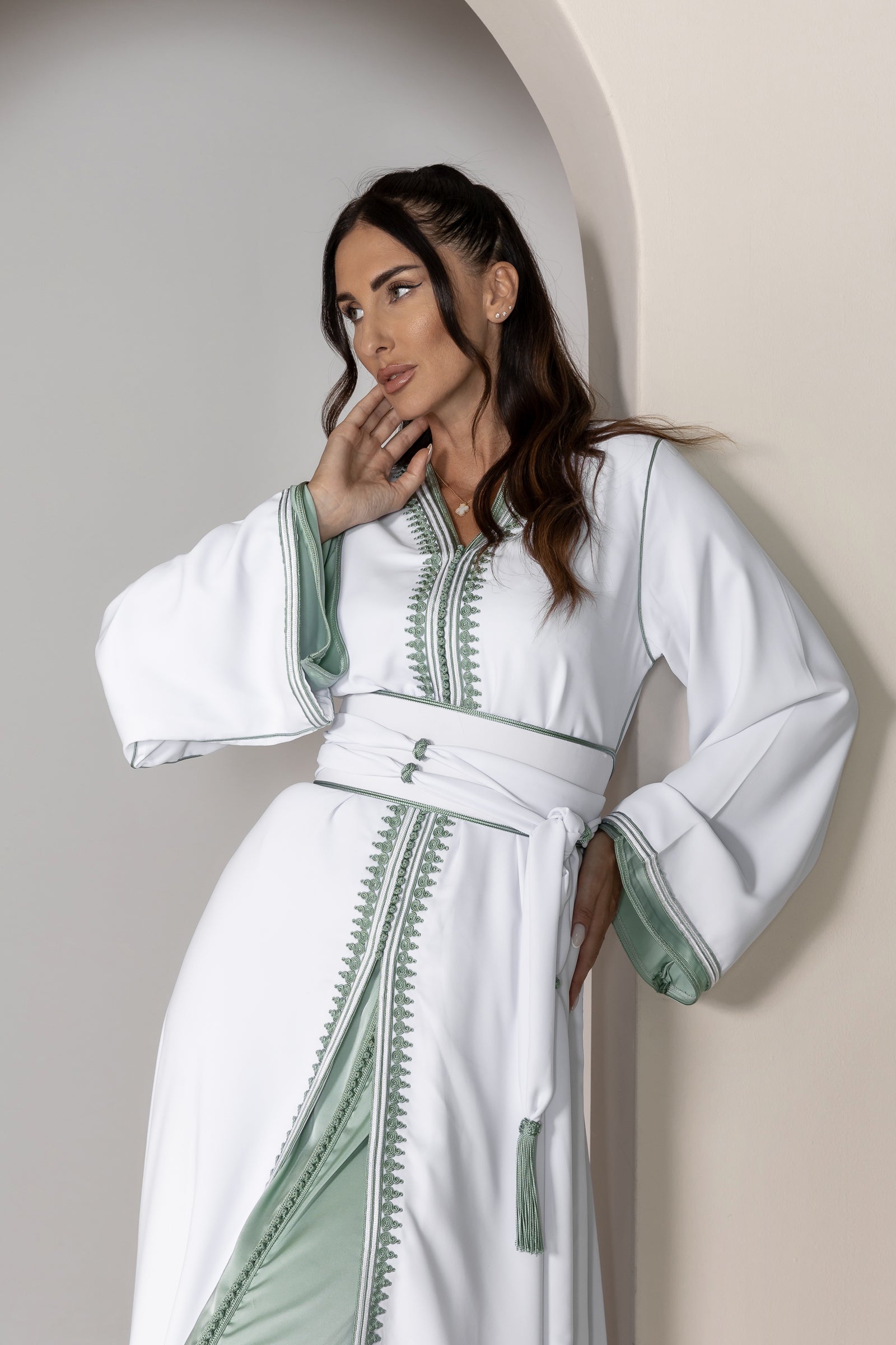 Back view of a white Moroccan kaftan with green trim and flowing fabric