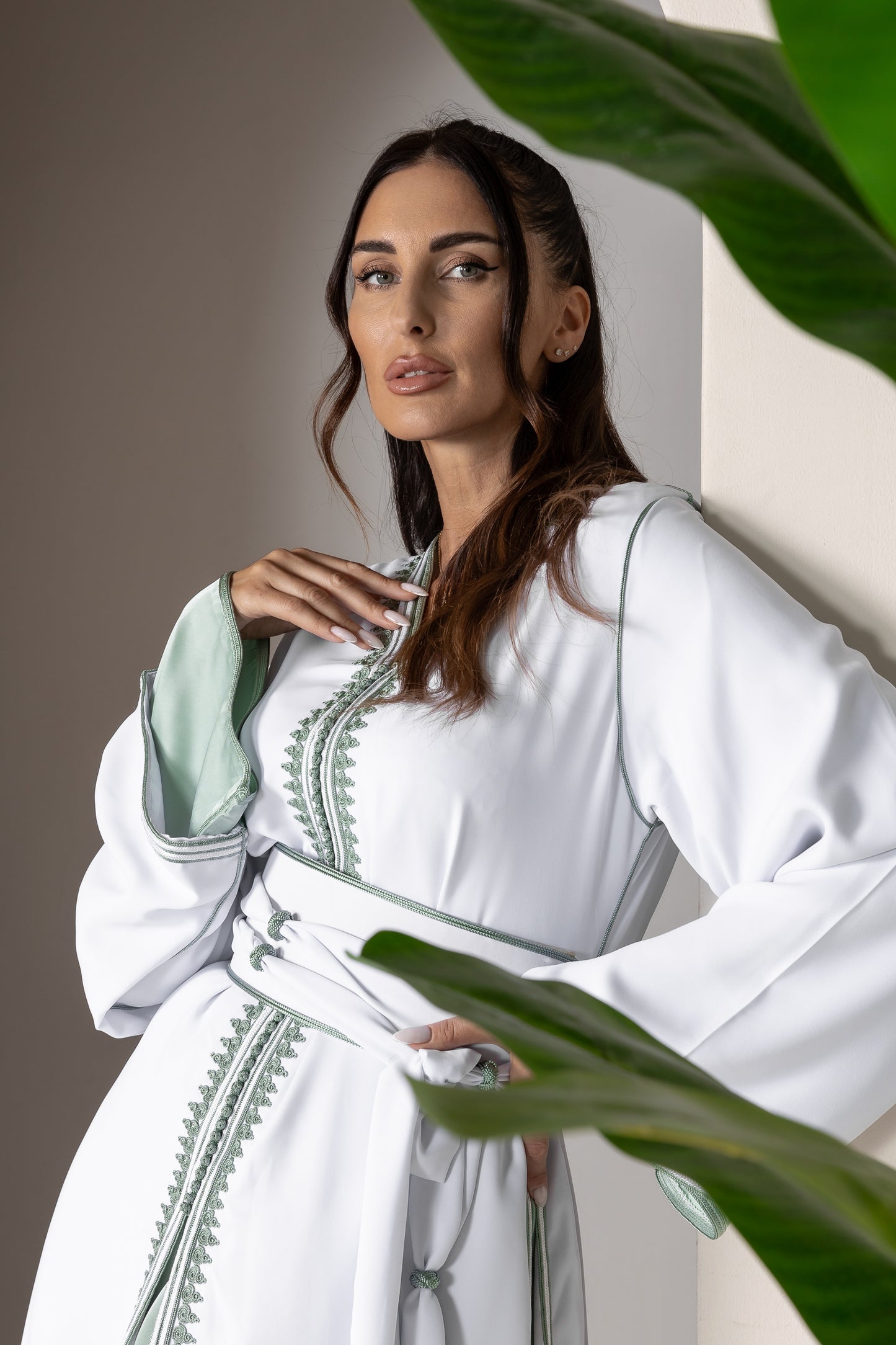 Close-up of white Moroccan kaftan showcasing green embroidery details