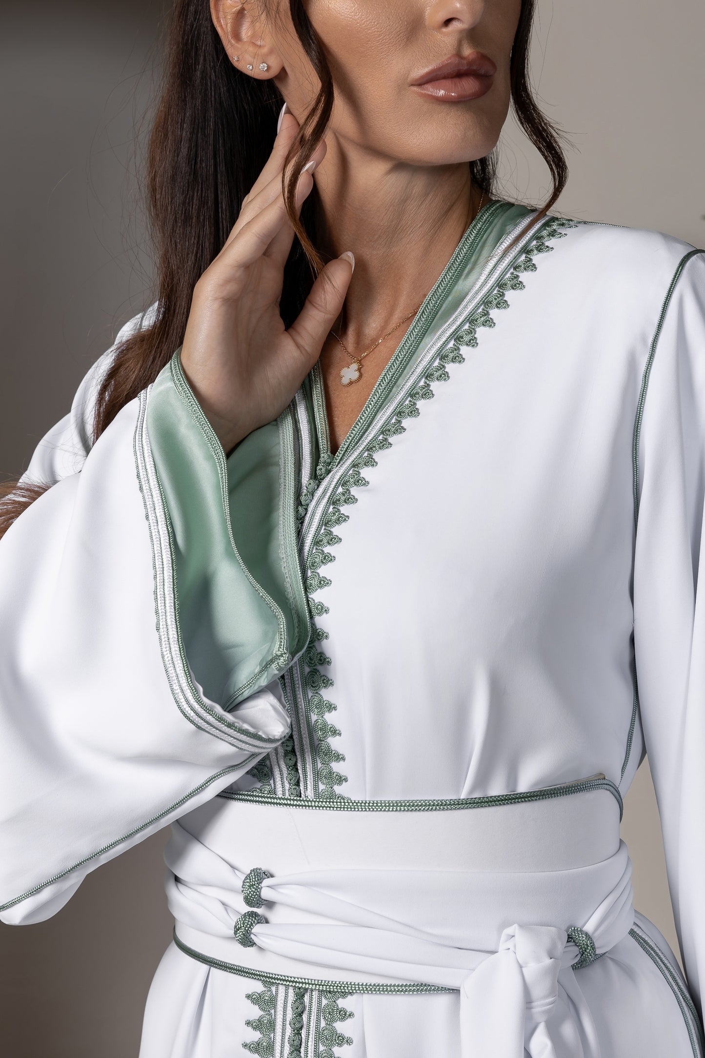 Detailed view of green embroidery on white Moroccan kaftan's neckline