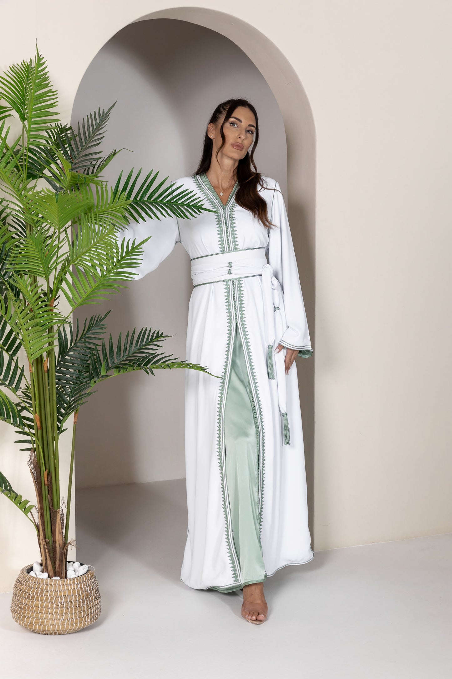 Woman in white Moroccan kaftan with green embroidery and a matching belt