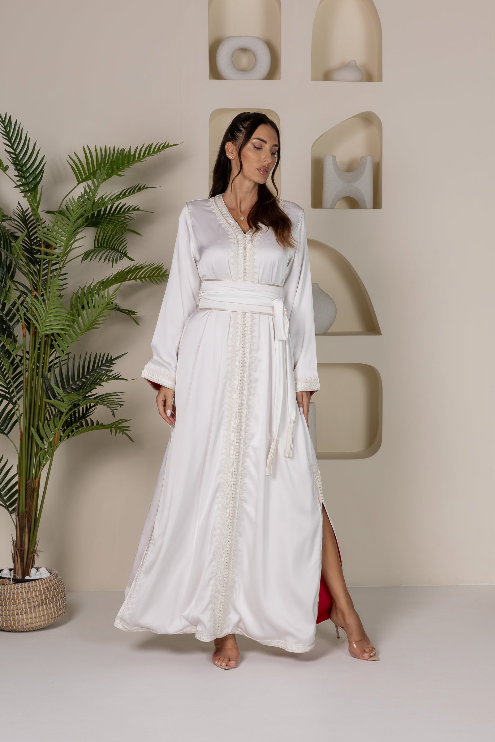 Woman in white Moroccan kaftan with wide sleeves and a tied belt